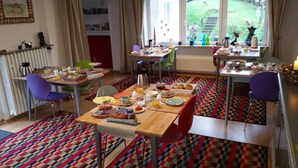 A dining area with a checkered floor, multiple tables set for breakfast, and chairs.