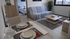 Ein modernes Wohnzimmer mit einer Couch, einem Couchtisch und einem Essbereich für zwei Personen.