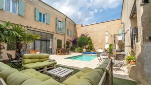 Une cour avec une piscine, du mobilier d’extérieur et un espace repas.