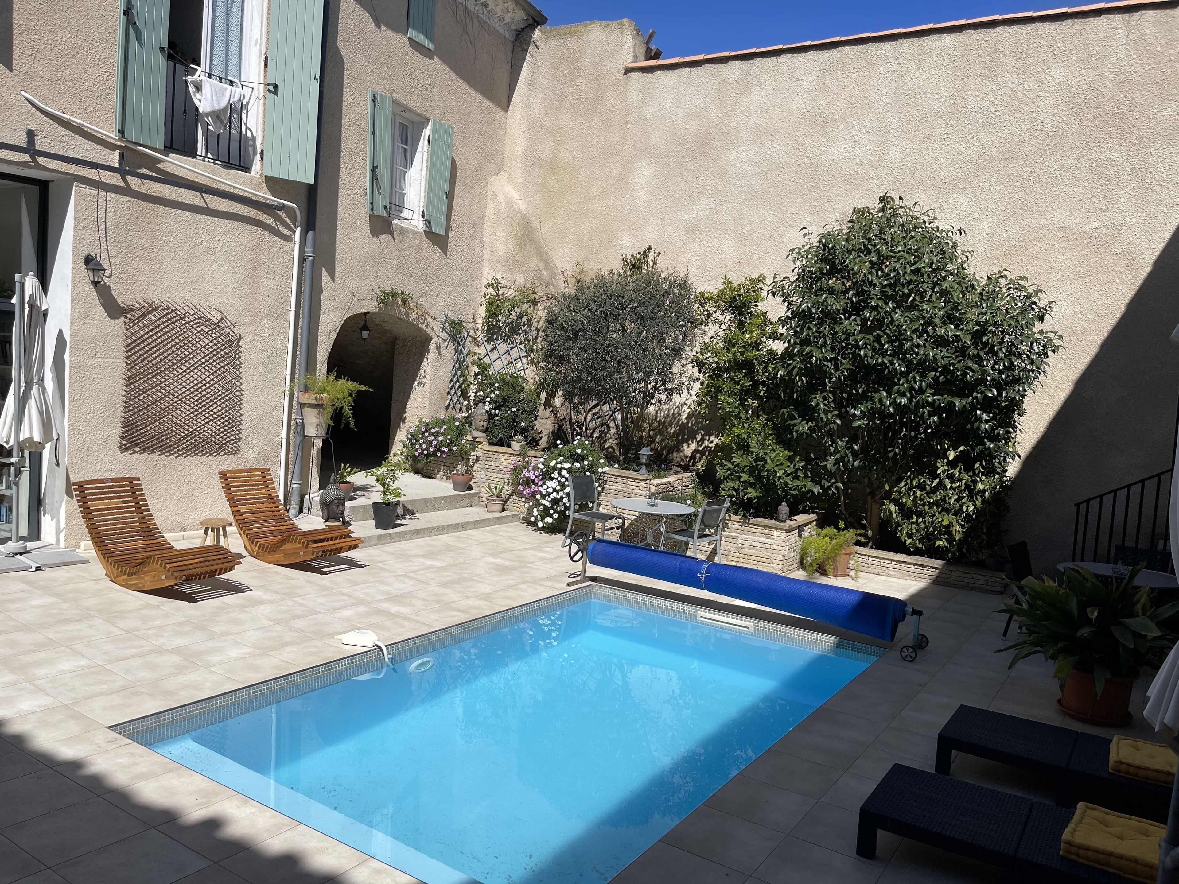 Una piscina con lettini, un tavolino e piante in vaso.
