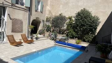 Una piscina con lettini, un tavolino e piante in vaso.