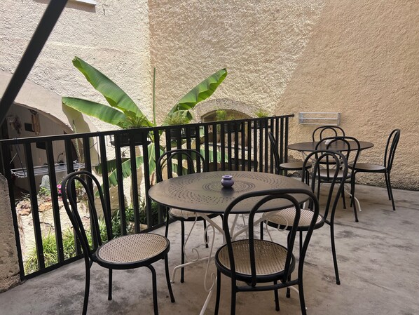 Un patio al aire libre con una mesa redonda y sillas, rodeado por una valla de metal negro.