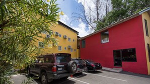Un estacionamiento con dos autos estacionados frente a un edificio amarillo y uno rojo.