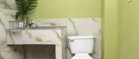 Un baño con un lavamanos de mármol, un inodoro y una pared verde.