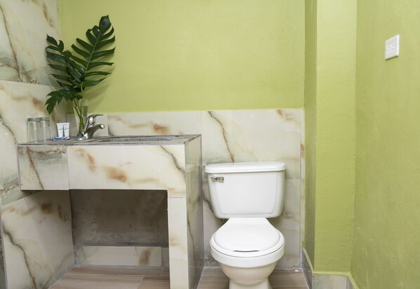 Un baño con un lavamanos de mármol, un inodoro y una pared verde.