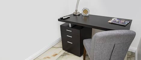 A modern office desk with a lamp, clock, and remote control.
