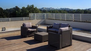 Eine Dachterrasse mit Korbmöbeln und Blick auf die Stadt.