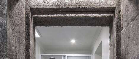 Ein Badezimmer mit Steinwand, Waschbecken mit Spiegel und zwei Handtüchern an Handtuchhaltern.