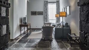 Ein Zimmer mit einem Steingewölbe, einem Sofa, einem Tisch und einer Lampe.