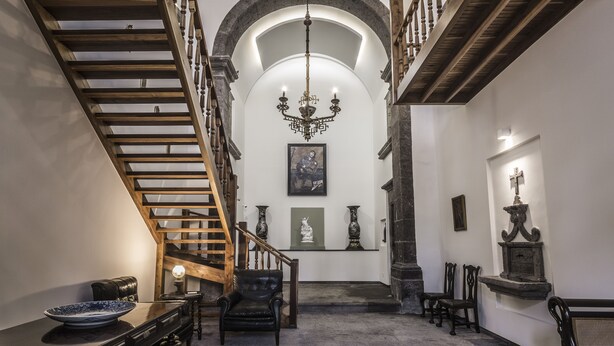 Eine prächtige Treppe mit hölzernen Geländern, einem Chandelier und klassischen Statuen.