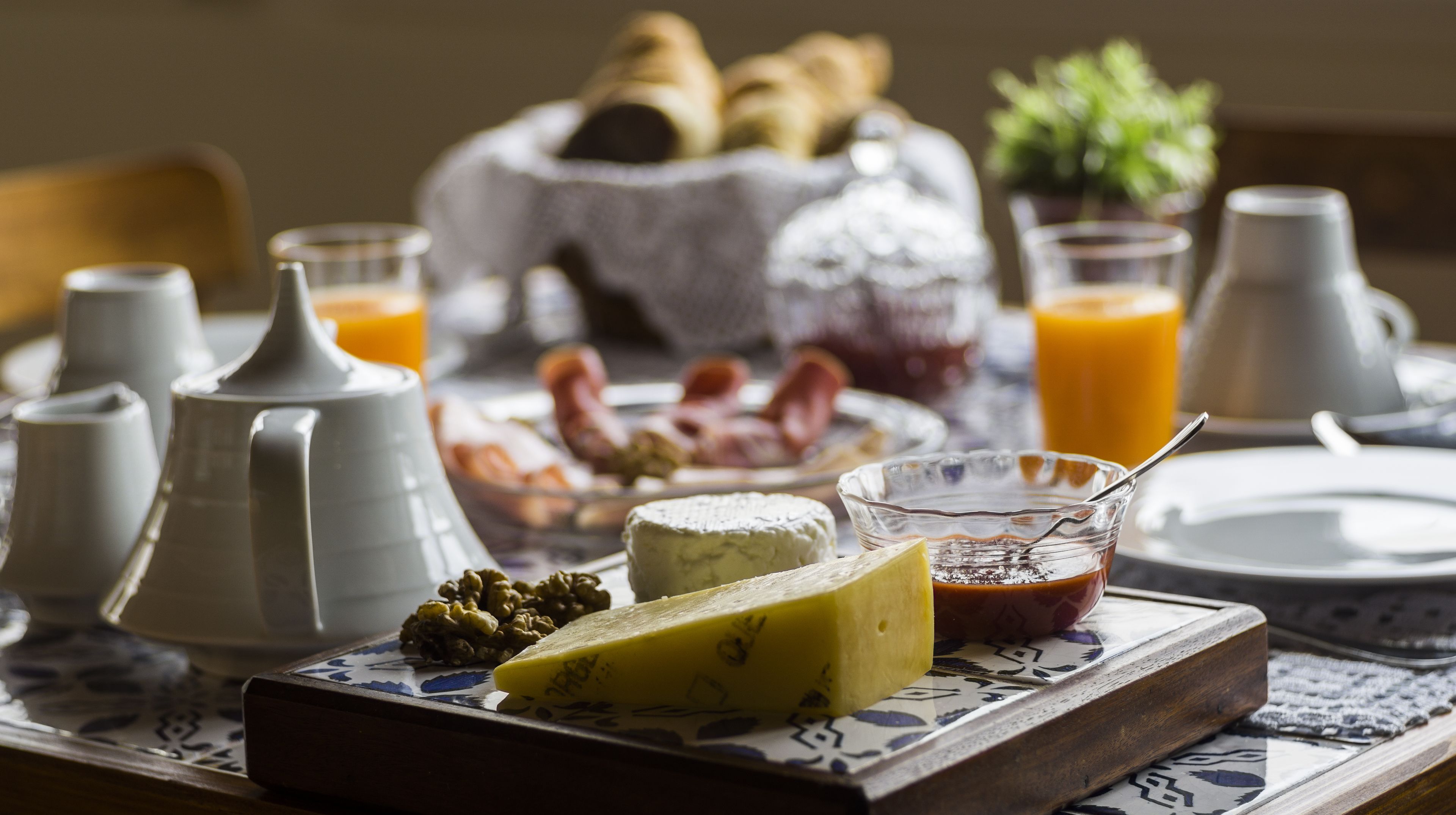A breakfast table with cheese, jam, and croissants.