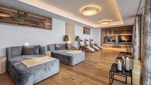 A modern living room with grey sofas, a wooden floor, and a dining area with a wooden table and chairs. - Aktivhotel Gasteiner Einkehr (Dorfgastein)