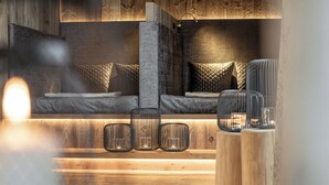 A cozy seating area with a bench and cushions, a small table with a candle, and a wooden bench with a metal railing. - Aktivhotel Gasteiner Einkehr (Dorfgastein)