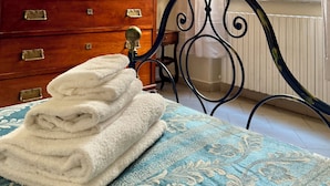 A bedroom with a bed, a dresser, a window with curtains, and a wall-mounted lamp. - Lucca Charm (Lucca)