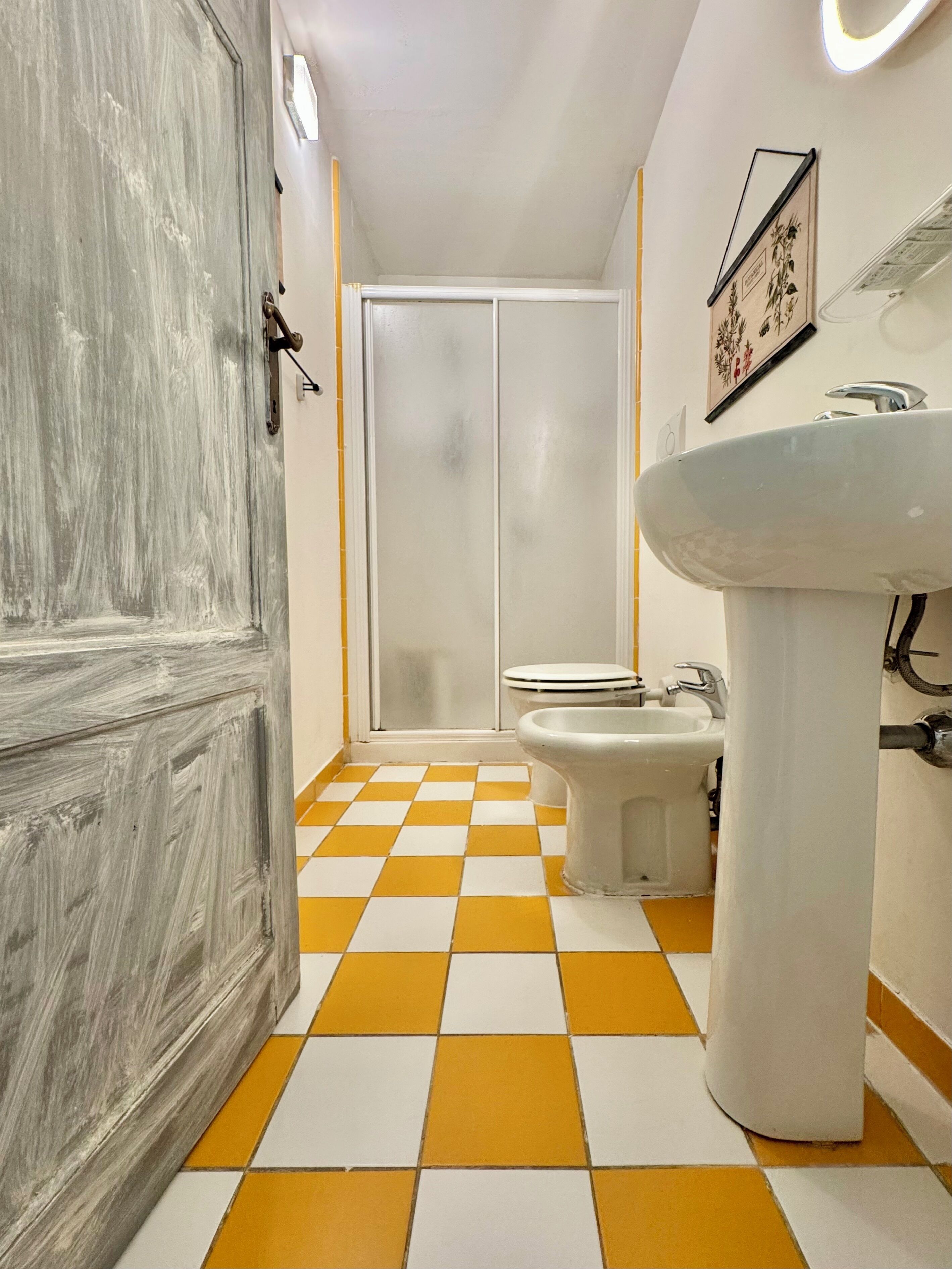 Un baño con piso a cuadros, un lavamanos, un bidé y un inodoro.