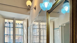 A bathroom with a large mirror, two sinks, a toilet, and a window with curtains. - Lucca Charm (Lucca)