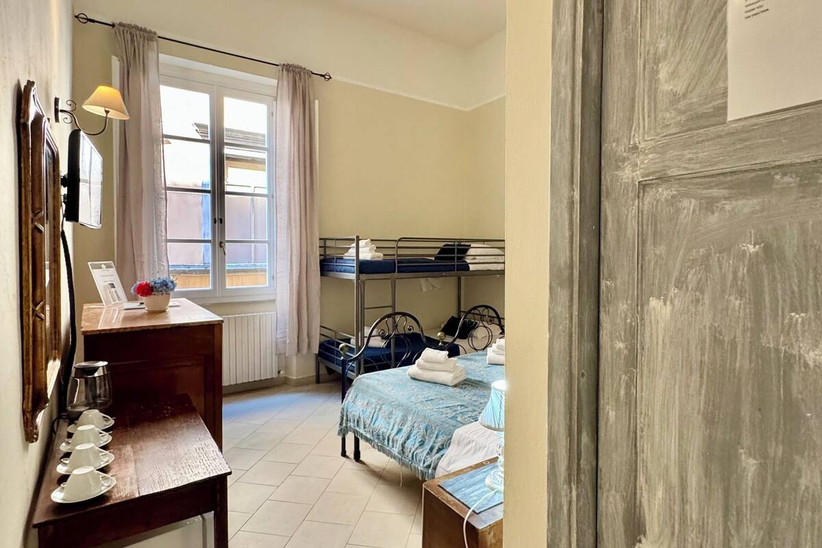A bedroom with a bunk bed, a desk with a lamp, and a window with curtains.