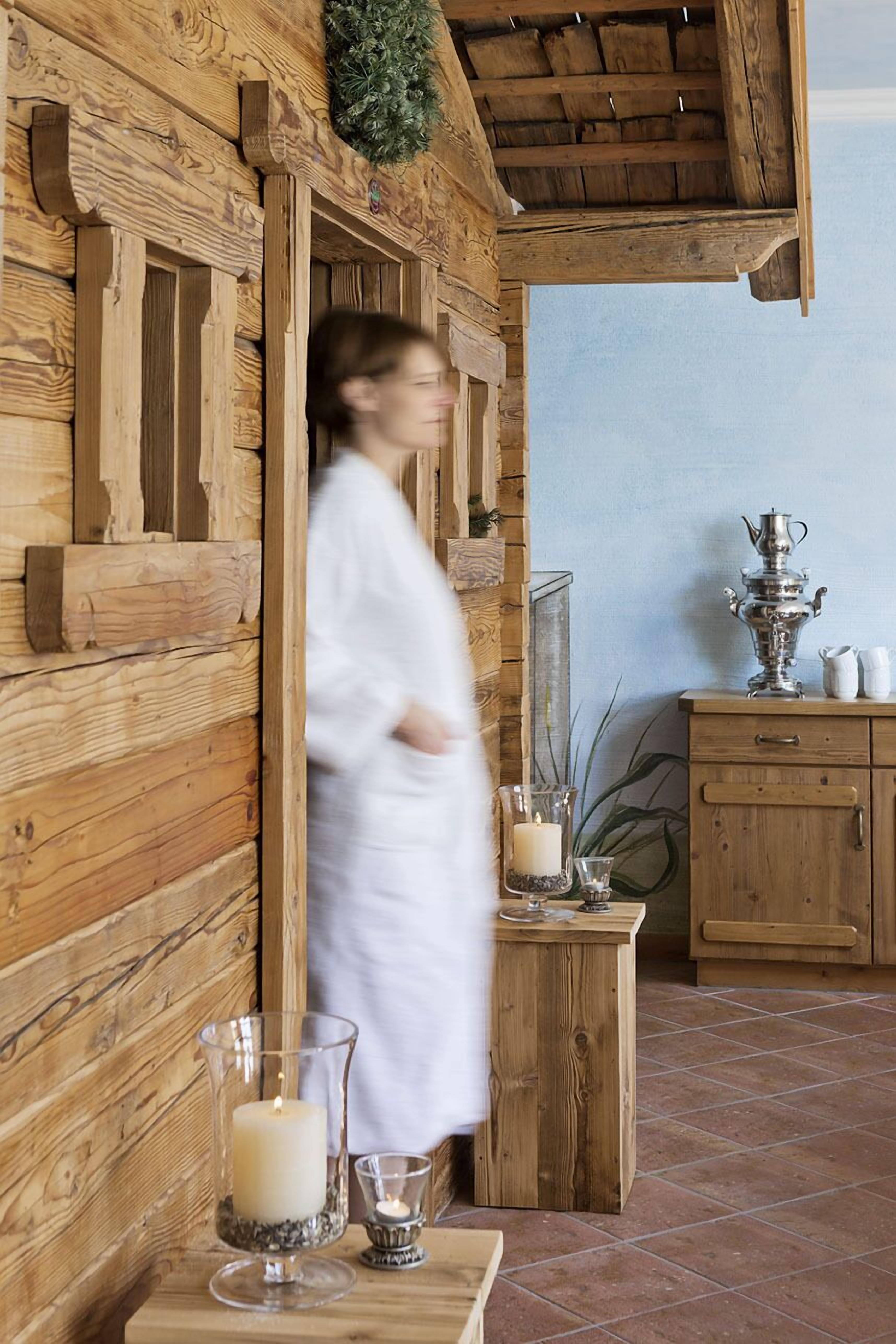 Ein Holzblockhaus-Interieur im rustikalen Stil, mit einem Holzkabinett mit Spiegel, einem kleinen Tisch mit Kerzen und einem dekorativen Metallbehälter.