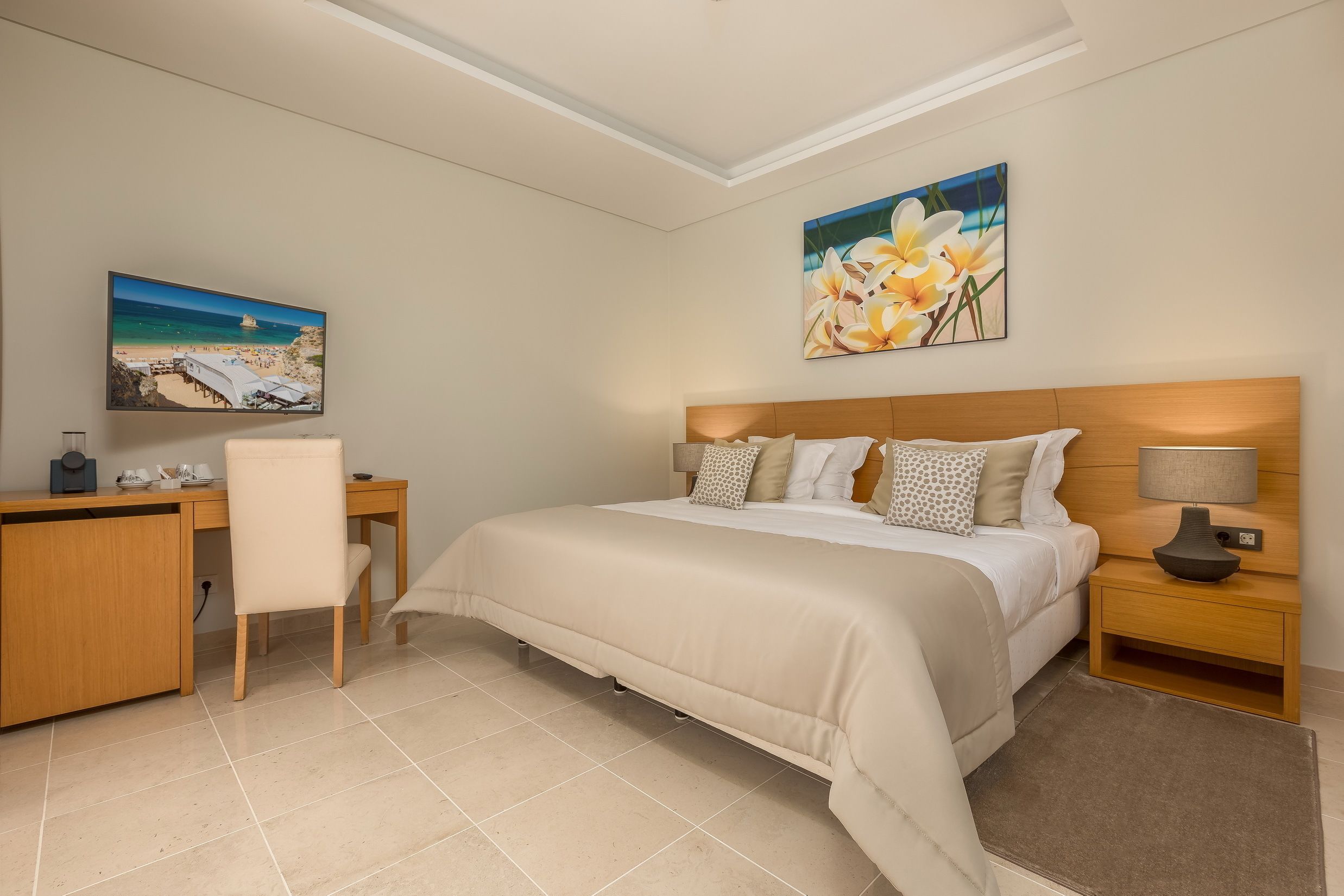 A bedroom with a bed, desk, chair, and artwork on the walls.