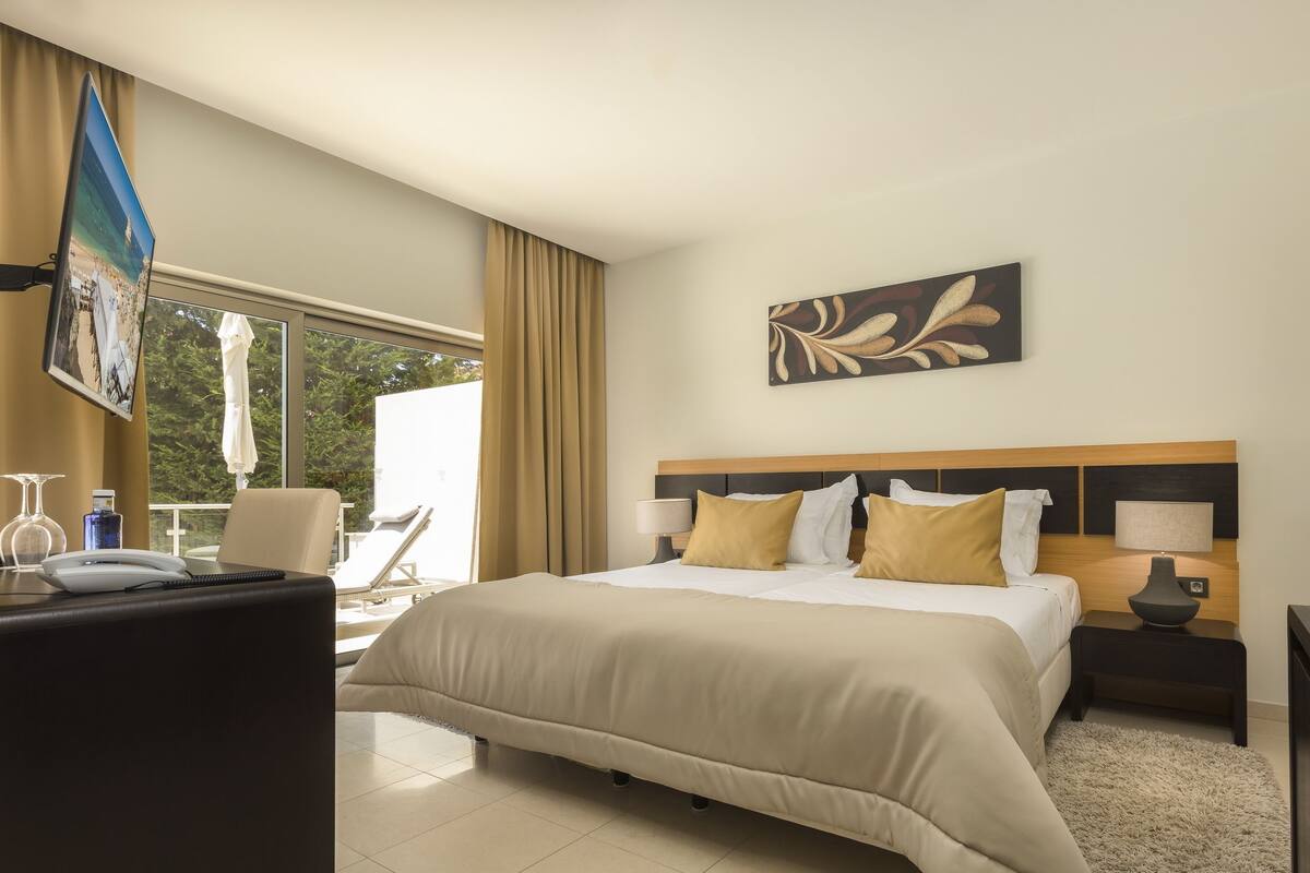 Een hotelkamer met een bed, nachtkastjes, een bureau en een stoel.