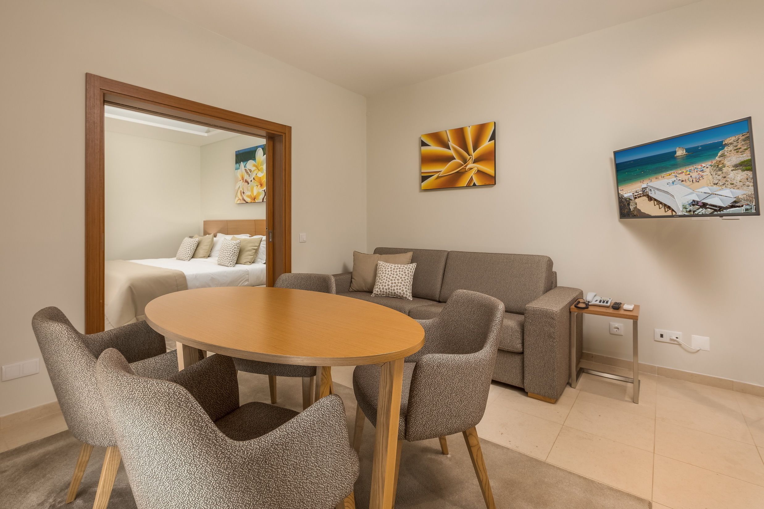 Un salon moderne avec une table ronde en bois et des chaises assorties, un canapé gris et un grand miroir.