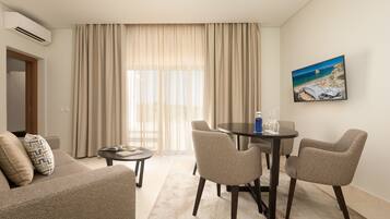 Suite, vista al mar | Área de sala de estar | Televisión de pantalla plana