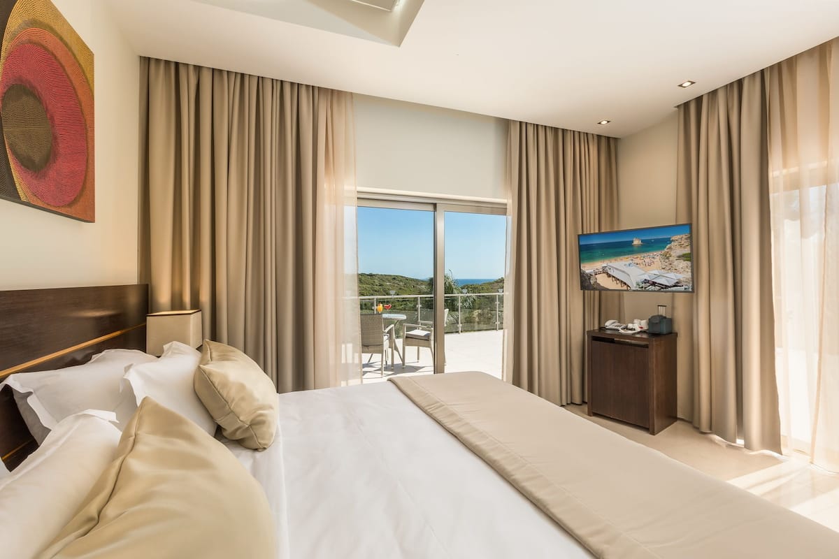 Een hotelkamer met een groot bed, een televisie en een balkon met een mooi uitzicht.