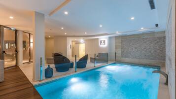 Relax by the rectangular pool surrounded by lounge chairs and a textured stone wall.