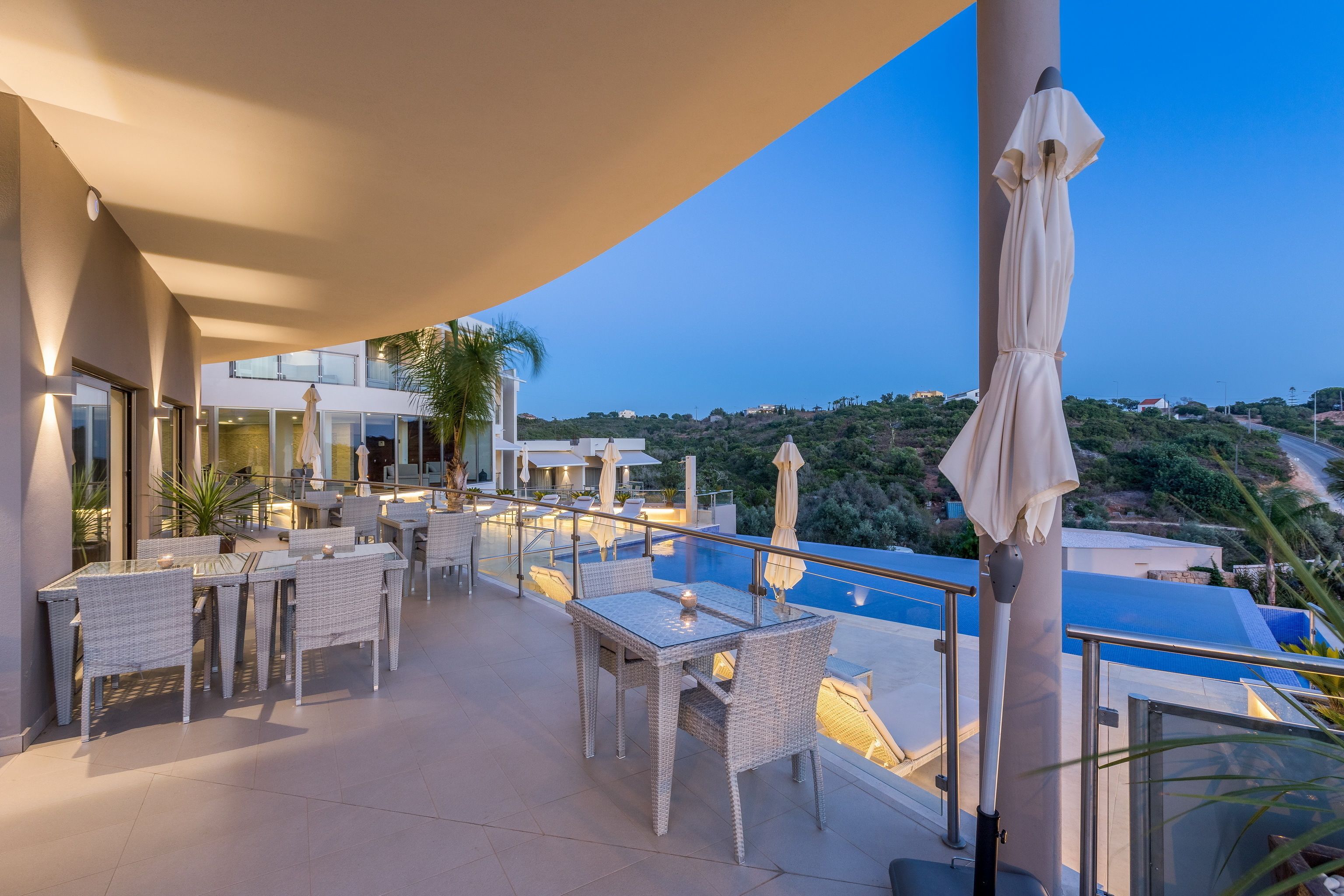Una terraza con asientos al aire libre, una piscina y vistas del paisaje circundante.