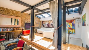 A modern interior with a glass table, red chairs, a white sofa, and a brick wall. - The Museum Penthouse (London)