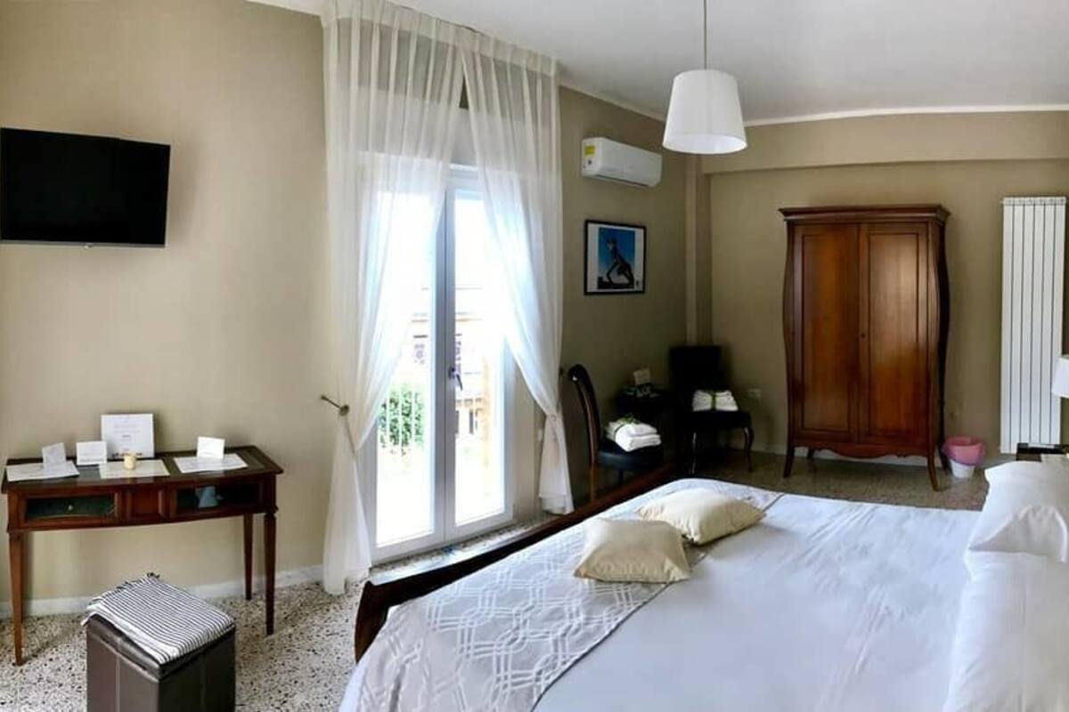 Une chambre d’hôtel comprenant un lit, un bureau, une chaise, une télévision et une armoire.
