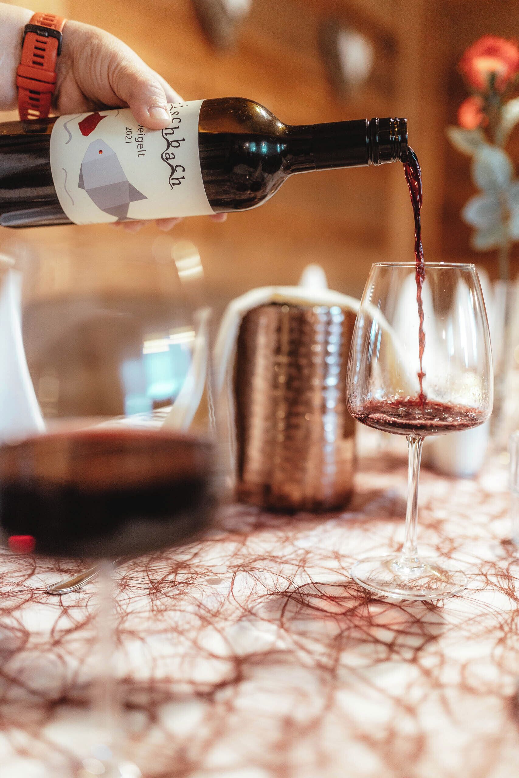 Una mano sirviendo vino en una copa.