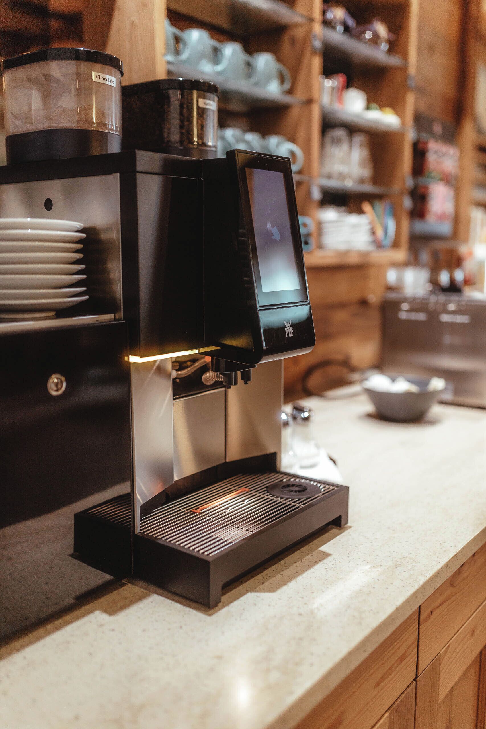 A modern coffee machine with a digital display, a water reservoir, and a drip tray on a kitchen counter.