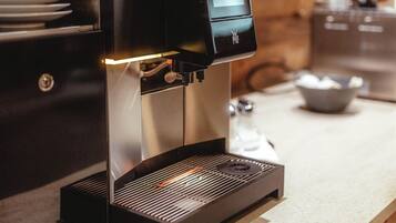 A modern coffee machine with a digital display, a water reservoir, and a drip tray on a kitchen counter.