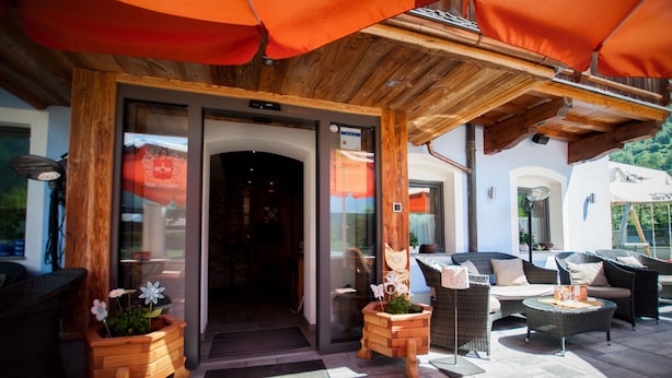 Ein Terrassenbereich im Freien mit Korbmöbeln, Topfpflanzen und einer Holzbeschichtung.