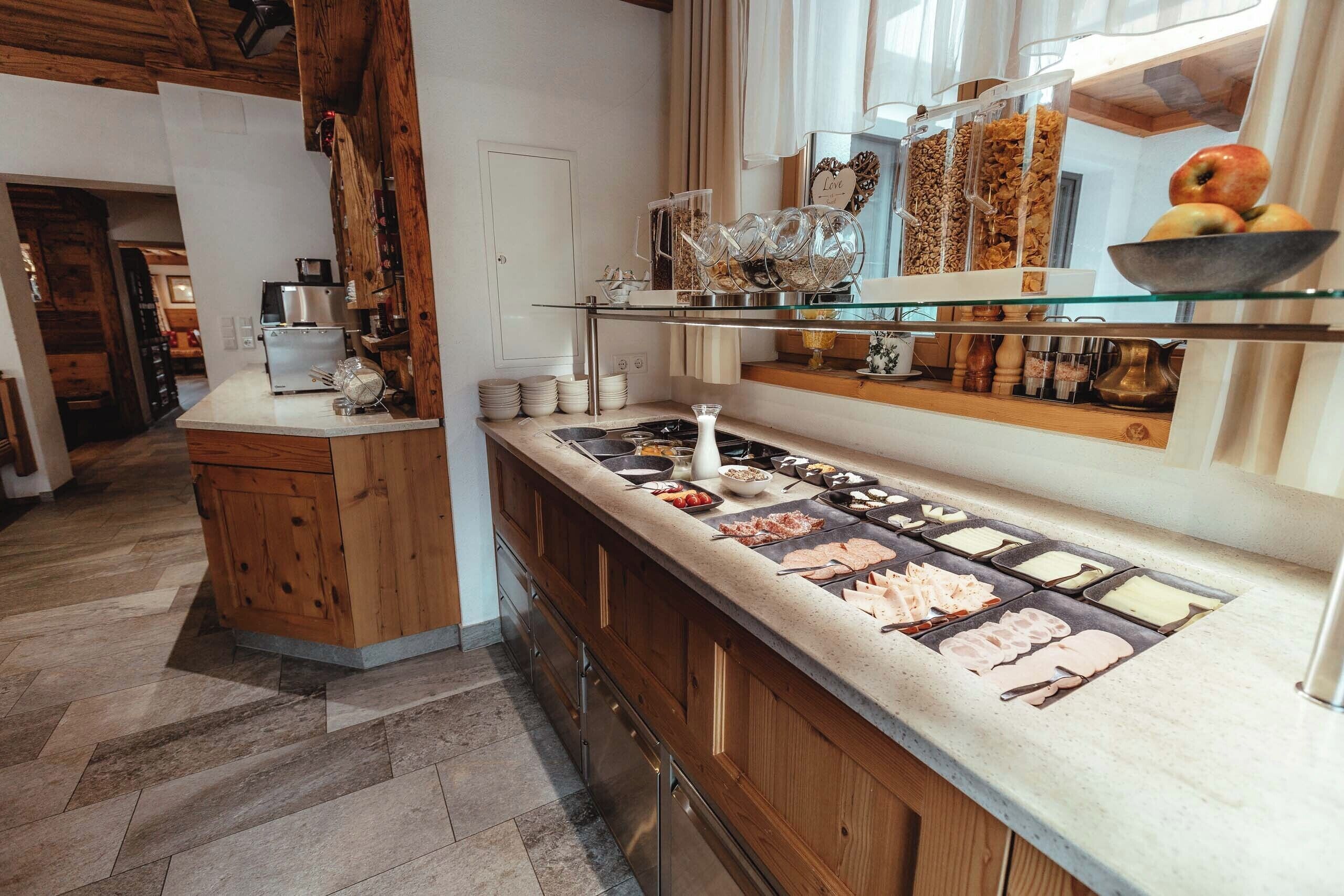 A kitchen with a long countertop, wooden cabinets, and a glass display shelf.