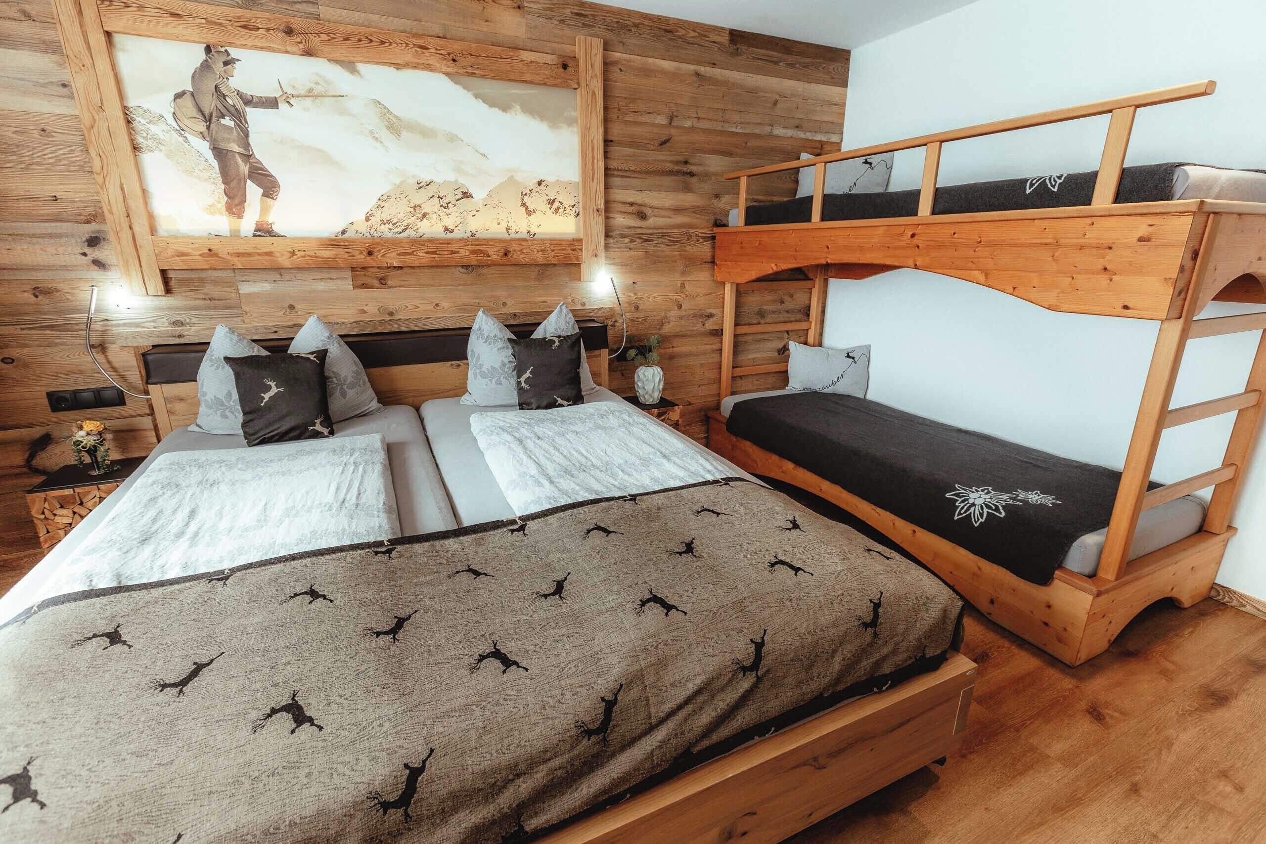 Quarto com beliche, duas camas de solteiro, paredes de madeira, um quadro e uma mesa de cabeceira com abajur.