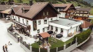 Ein traditionelles Chalet mit einer Terrasse, einer Spielanlage und einem Schild, das ein Restaurant anzeigt.