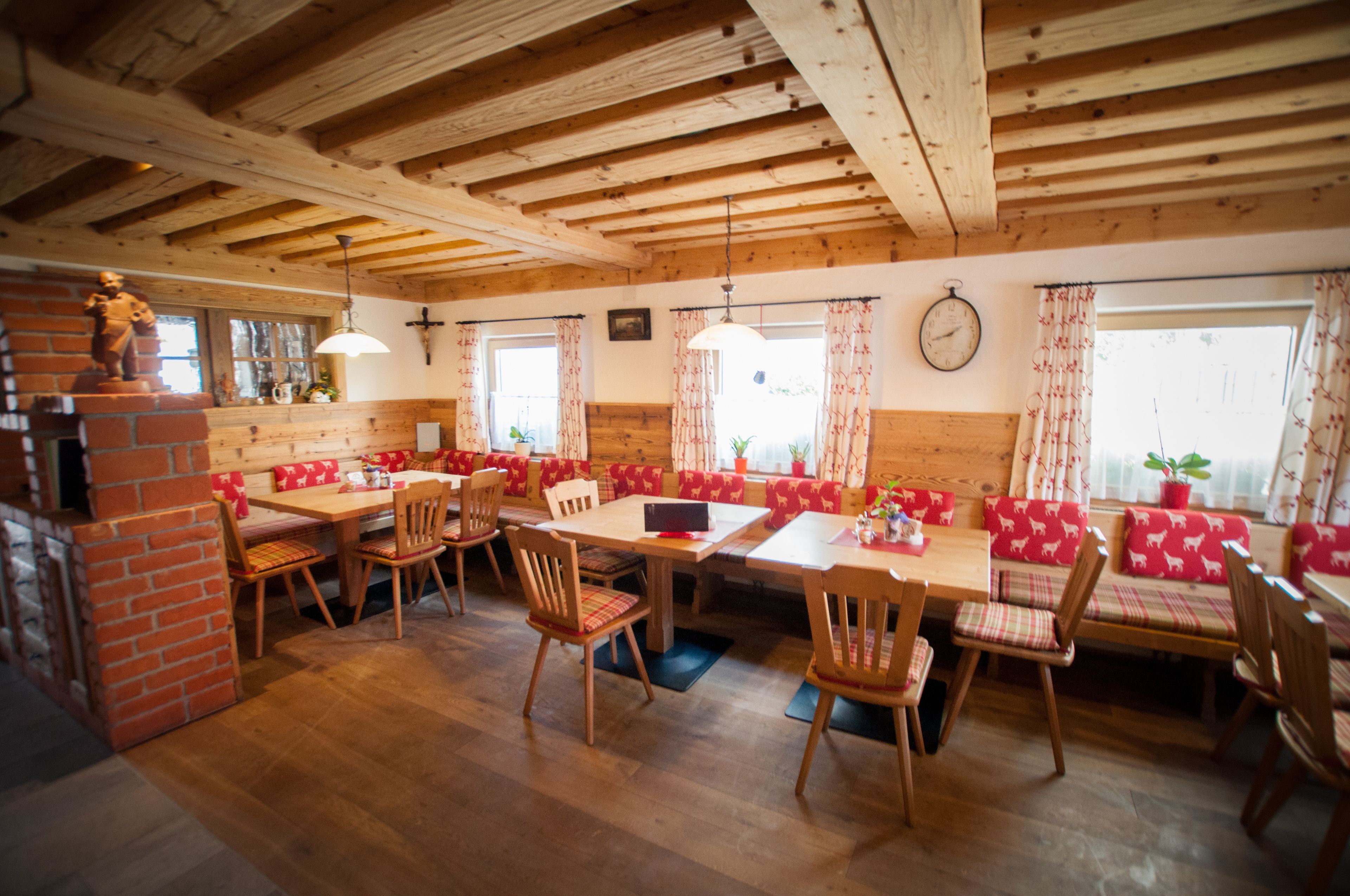 A rustic dining area with wooden tables and benches, brick walls, and a wooden ceiling.