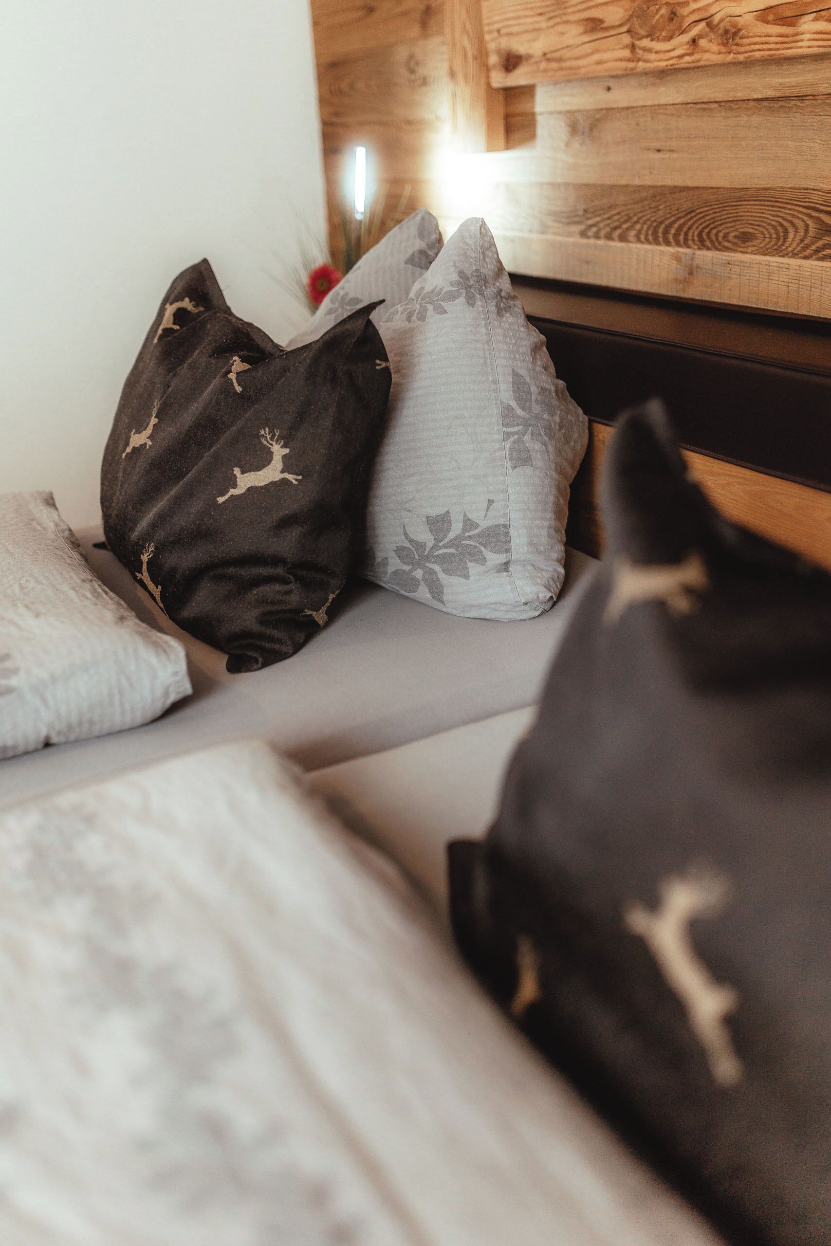 A bed with a grey headboard, multiple pillows, and a wooden headboard.