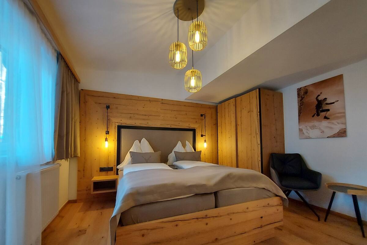 Un lit en bois avec une tête de lit, des lampes de chevet, une chaise et un tableau accroché au mur.
