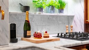 Una encimera de cocina con una botella de champán Moët & Chandon, dos copas y una tabla de madera con un postre.