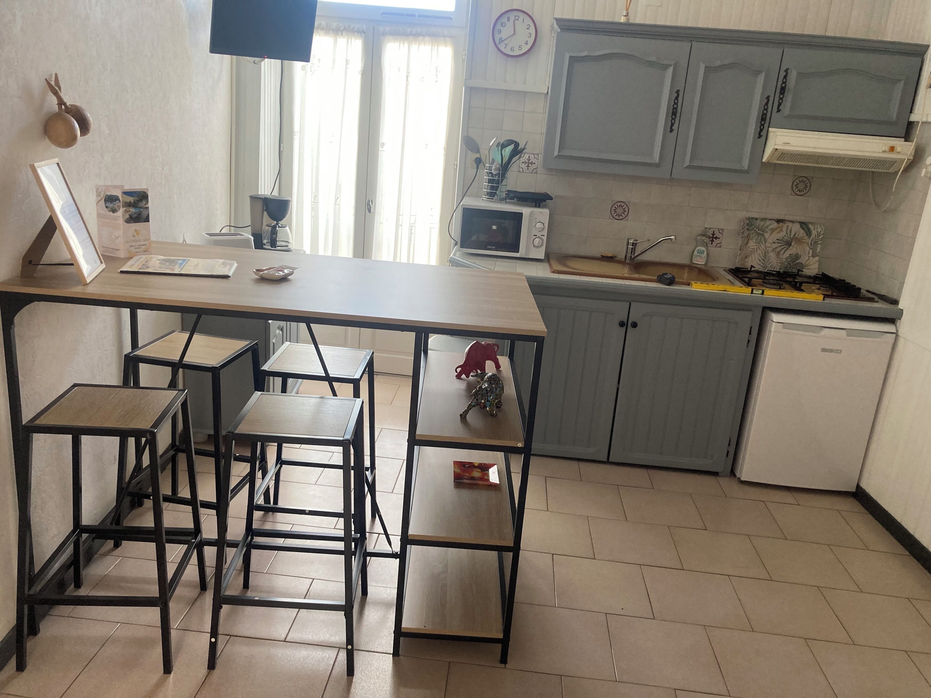 A kitchen with a wooden table, bar stools, a microwave, a sink, and cabinets.