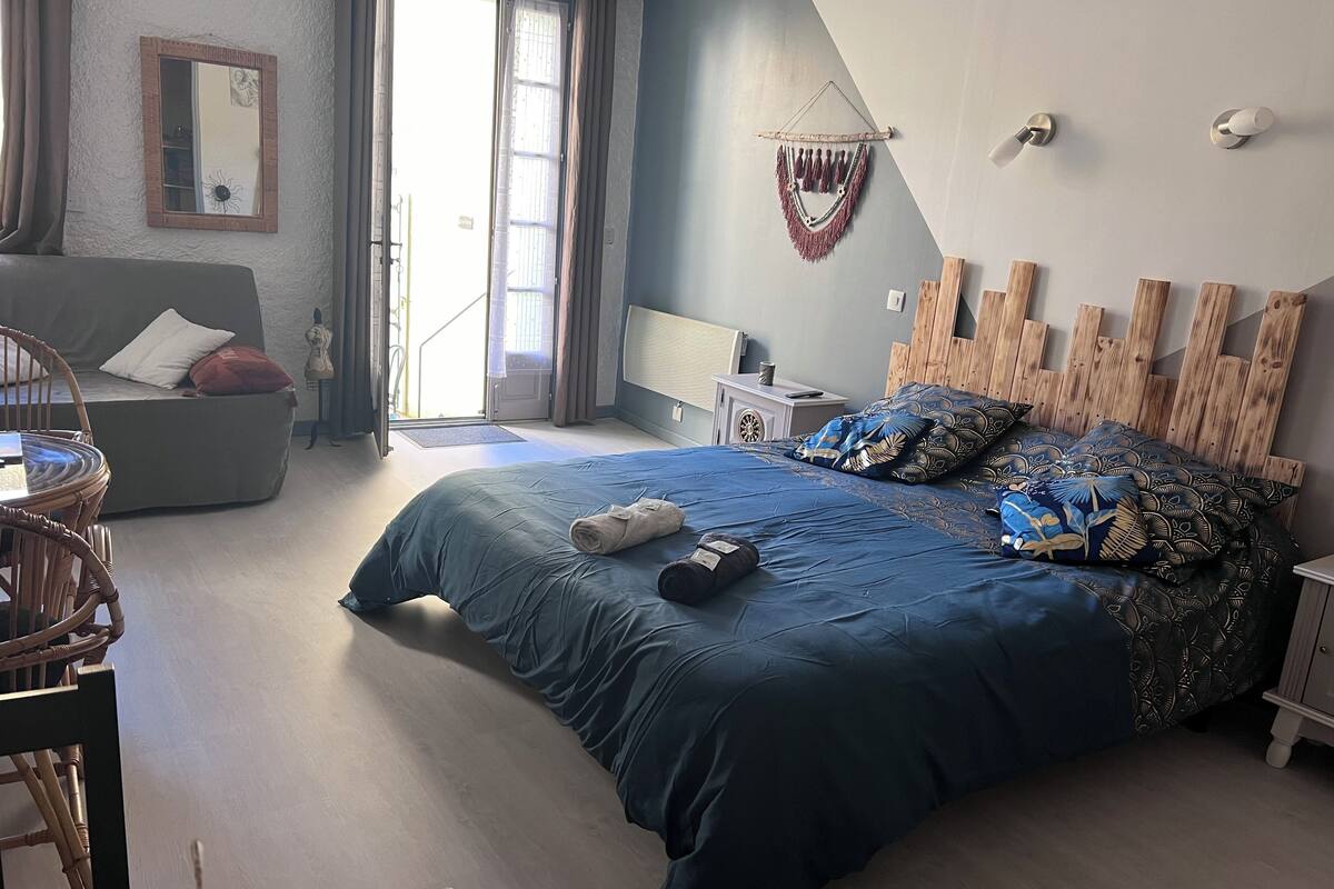 A bedroom with a large bed, a chair, a small table, and a nightstand.