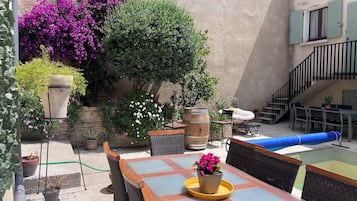 An outdoor patio with a table and chairs, surrounded by potted plants and a staircase.