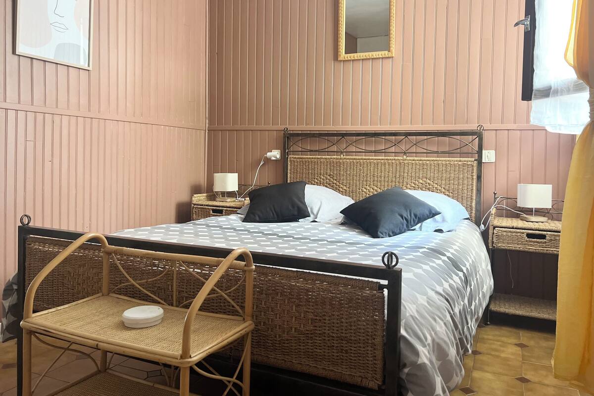 A bedroom with a bed, bedside tables, a chair, a mirror, and a wall-mounted picture.