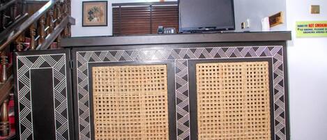 Un mostrador de recepción con un televisor, un teléfono y un cuadro en la pared.