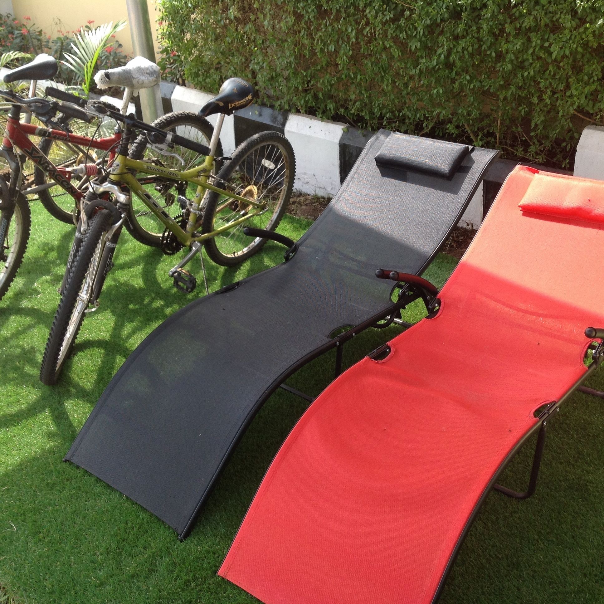A set of lounge chairs on artificial grass, with a bicycle parked nearby.