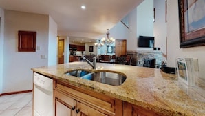 A kitchen with granite countertops, a stainless steel sink, wooden cabinets, and a built-in dishwasher.