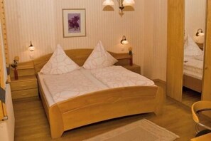 A bedroom with a wooden bed, two bedside tables, and a nightstand. - Haus Waldesruh (Hollnich)
